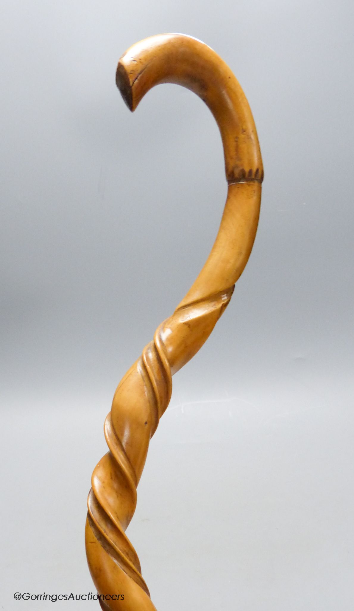 A carved wood walking stick in the style of a narwal tusk